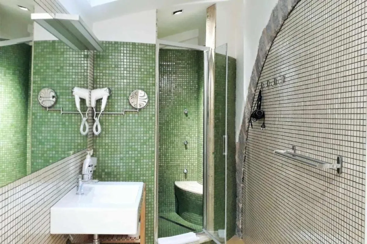 Bagno con mosaico verde e doccia in vetro