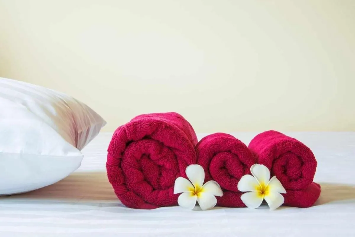 Asciugamani arrotolati con fiori bianchi sul letto
