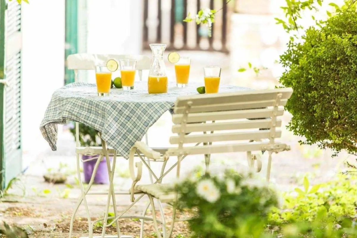 Tavolo apparecchiato in giardino con caraffa e bicchieri di spremuta d'arancia