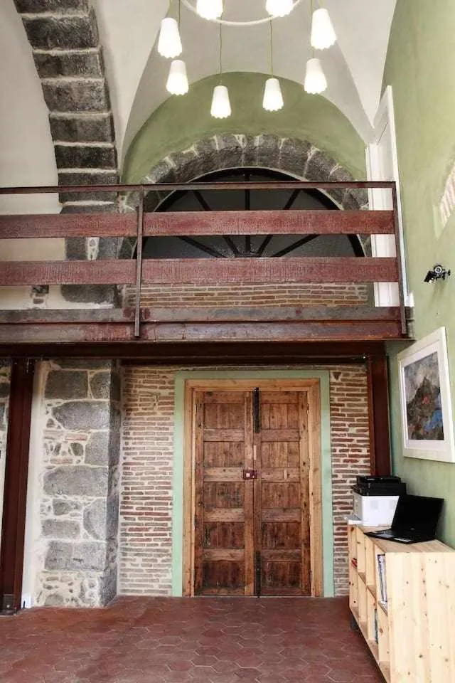 La doppia porta in legno del palazzo, sotto un arco in pietra lavica e il soppalco in legno