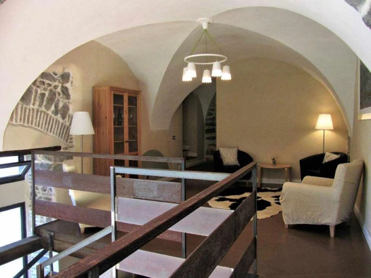 Salone con volte bianche, archi in pietra lavica e poltrone chiare